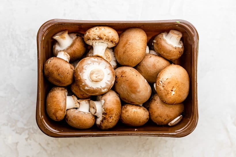 Mini portobello mushrooms in container before cleaned