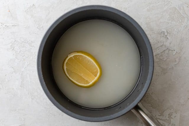 Making simple syrup with water, sugar and lemon slice along with rose water