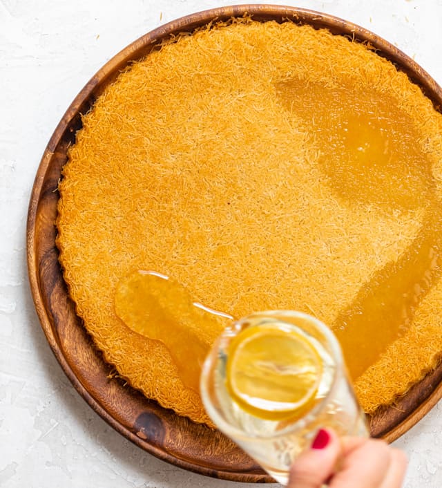 Pouring simple syrup over the finished kanafa