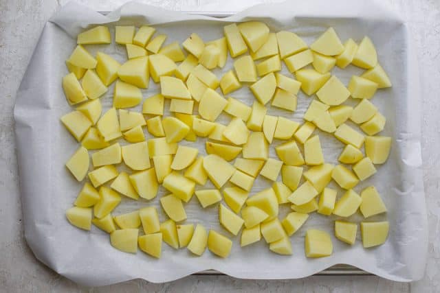 Baking dish with parchment paper and potatoes cut into small cubes