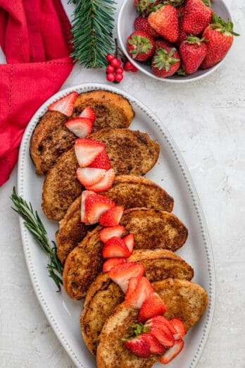 Vegan french toast on a long serving platter with sliced strawberries on top