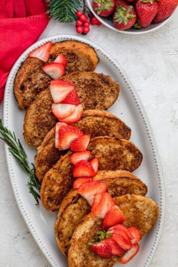 Vegan french toast on a long serving platter with sliced strawberries on top