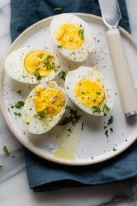 Easy hard boiled eggs made in air fryer cut in half on a white plate
