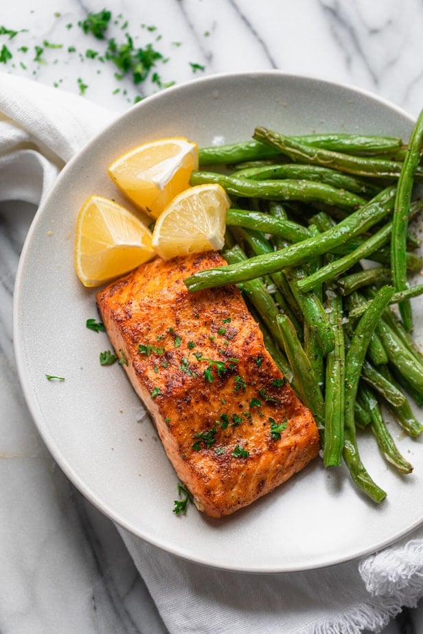 Plate with salmon and green beans with lemon wedges