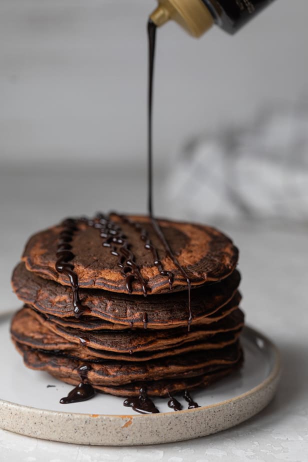 Drizzling chocolate syrup over the pancakes