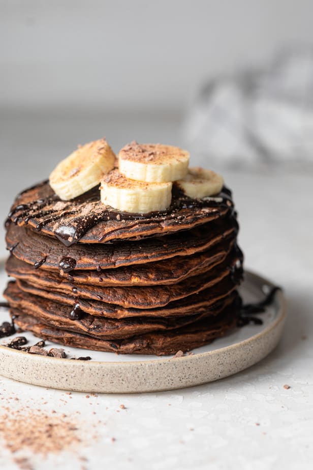 Chocolate protein pancakes topped with sliced bananas and cocoa powder