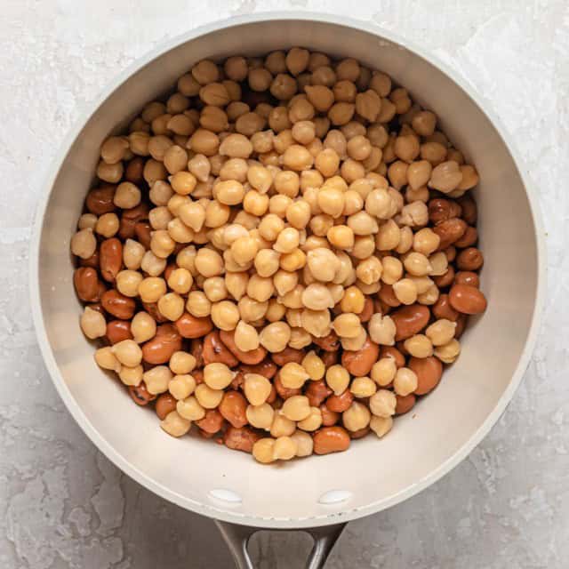 Beans and chickpeas added to a pan.