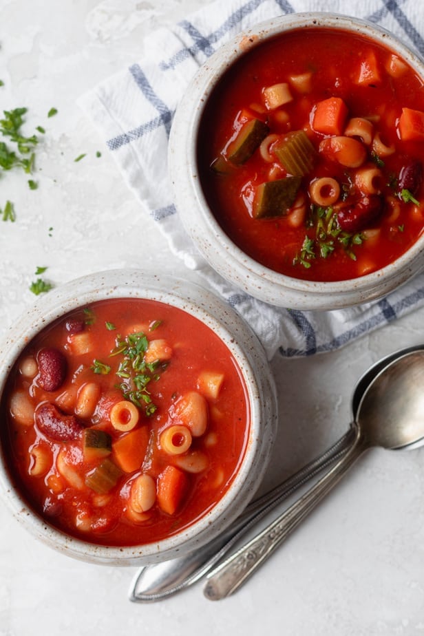 Zwei Becherschalen voller vegetarischer Minestronesuppe mit Löffeln daneben