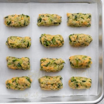 Shaped zucchini tots on a baking dish.