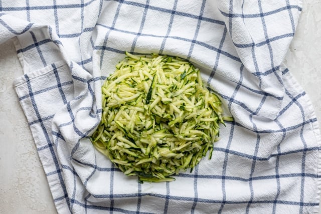 shredded zucchini on a kitchen towel before drying