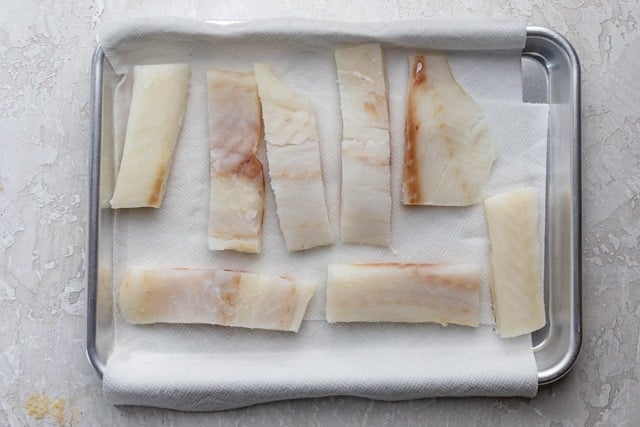 Cod fish cut into long fillets drying on paper towel