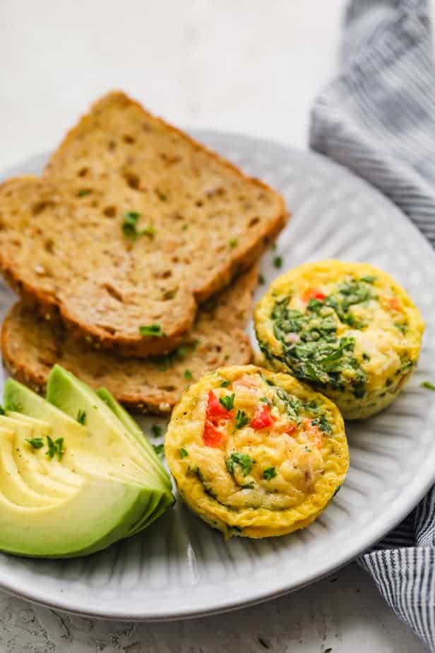 Breakfast egg cups served on a plate with toast and avocados
