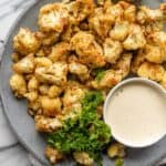 Oven roasted cauliflower with tahini on a plate with parsley