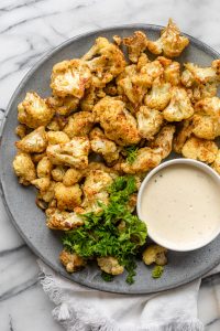 Oven roasted cauliflower with tahini on a plate with parsley