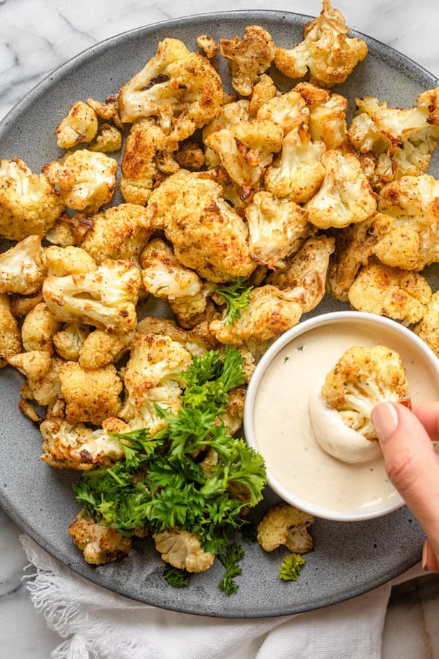 Dipping the oven-baked cauliflower into the tahini sauce