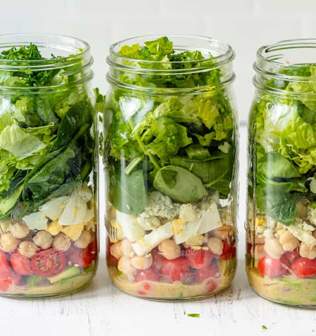 Filling in the jars with the remaining ingredients for the vegetarian cobb salad