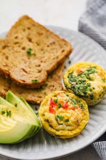 Breakfast egg cups served on a plate with toast and avocados