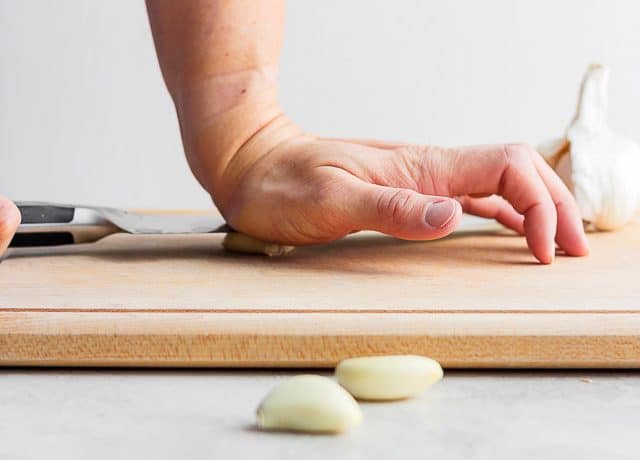 Crushing garlic with knife and hand