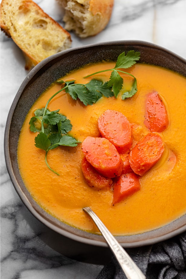 Carrot and ginger soup garnished with fresh coriander and roasted carrots