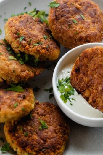 Chickpea fritters on a plate with a bowl of dipping sauce.