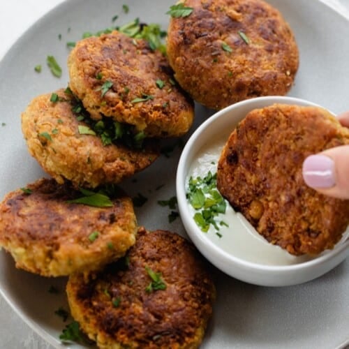 Chickpea fritters on a plate with a bowl of dipping sauce.
