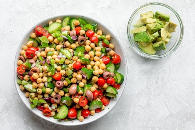 The chickpea salad ingredients tossed with the dressing in a white bowl