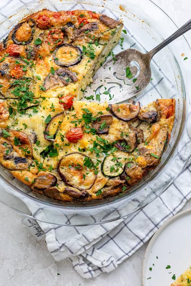 Quiche sans croûte dans un plat de cuisson avec une tranche retirée.