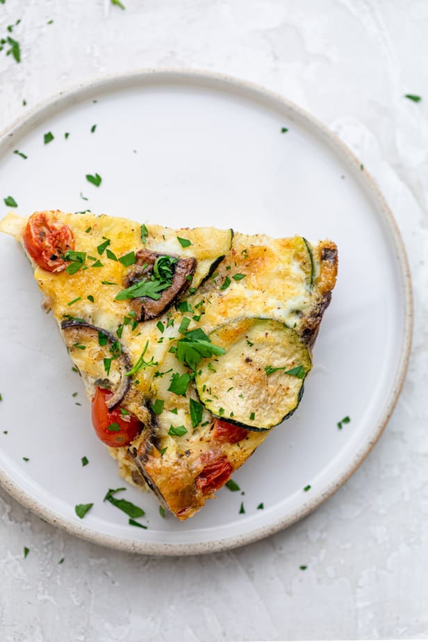 A slice of crustless quiche on a white plate