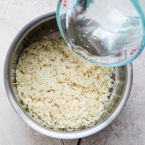 Pouring water on top of rice.