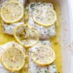 four fillets of baked cod in a white dish