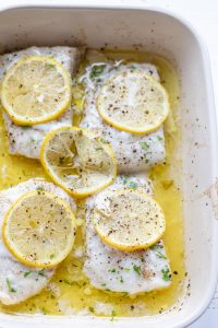four fillets of baked cod in a white dish