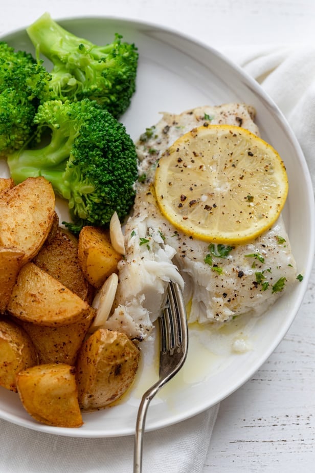 baked cod on a plate with potatoes and broccoli 