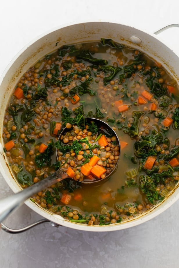 bowl of lentil kale soup with a ladle