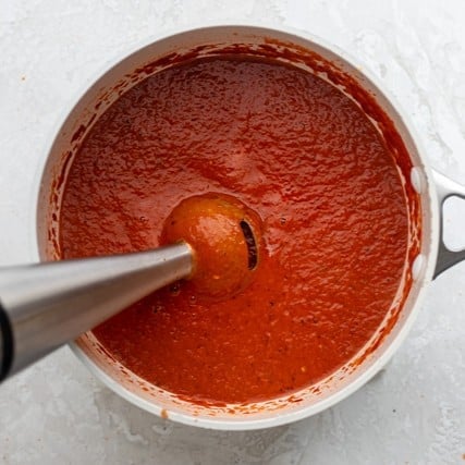 Blending the soup with an immersion blender.