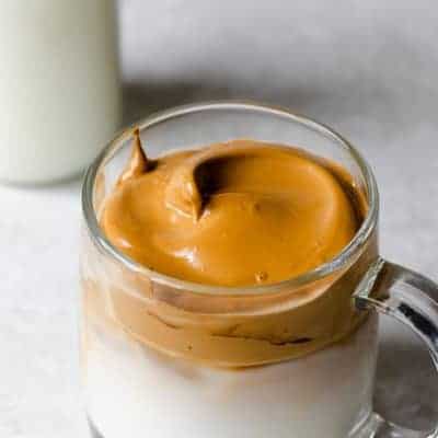 Peaks of whipped coffee in a glass mug over iced milk