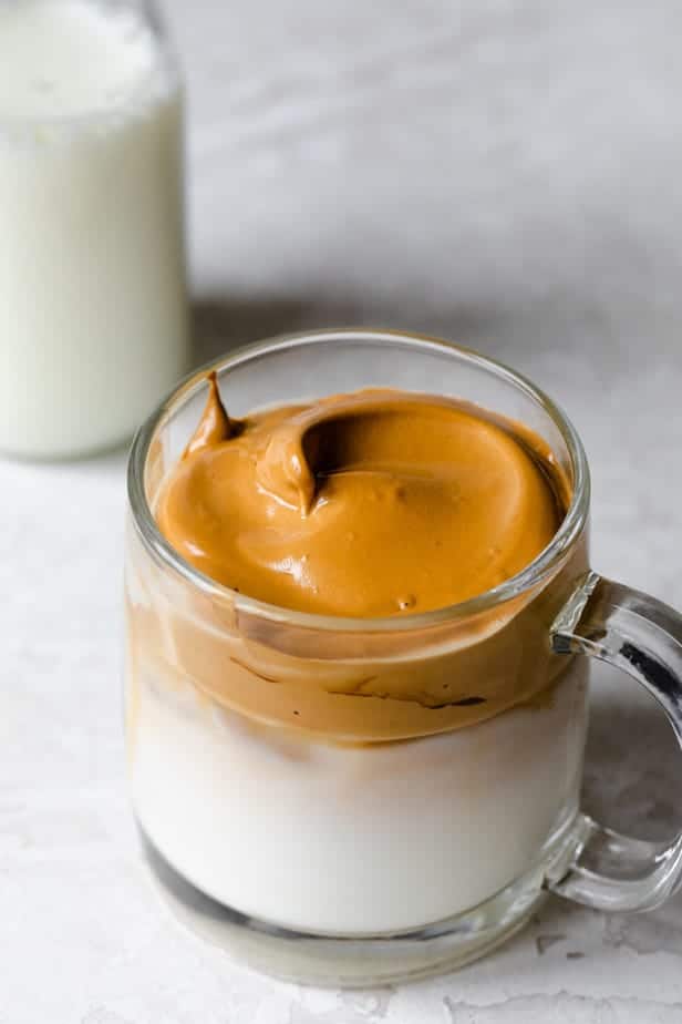 Peaks of whipped coffee in a glass mug over iced milk