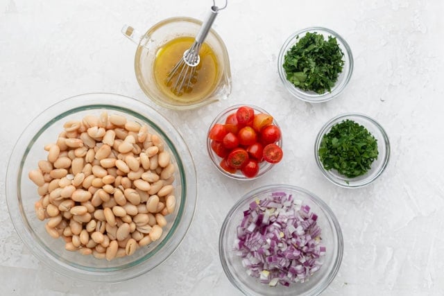 The white bean salad ingredients in glass bowls