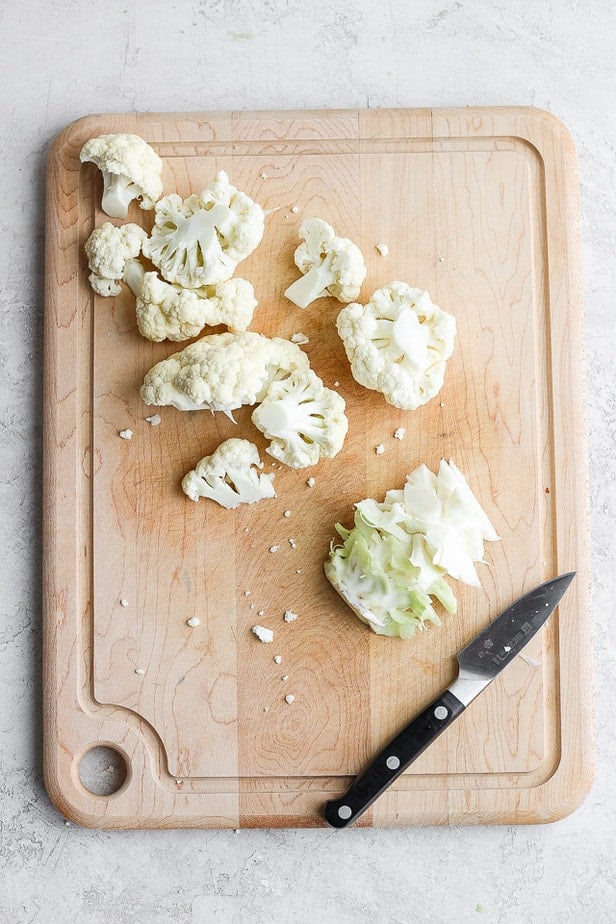 Cut cauliflower florets on a cutting board with a knife - tutorial for how to cut cauliflower