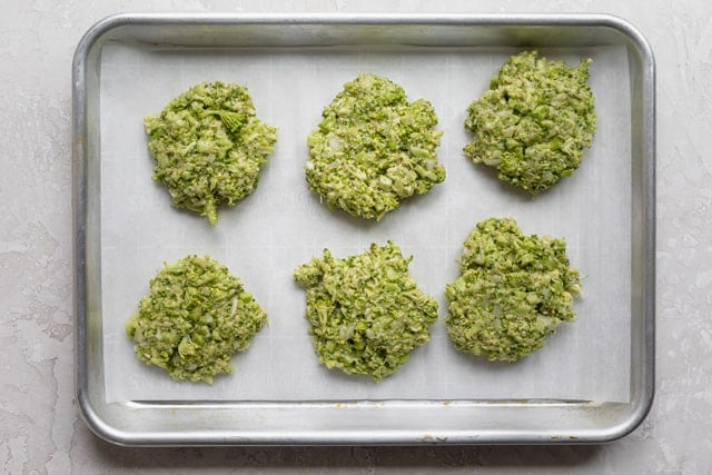 Broccoli patties formed and resting on parchment paper before frying