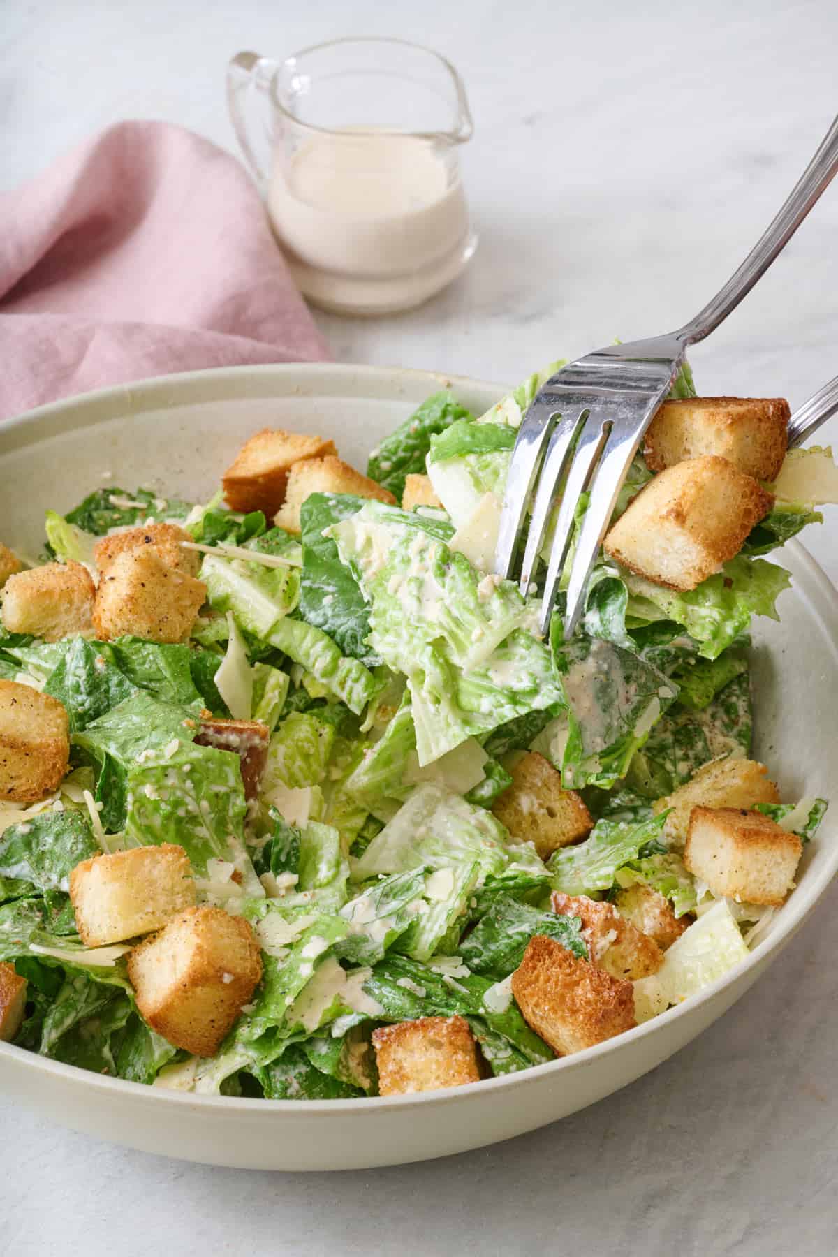Caesar salad in a bowl with a fork nearby.
