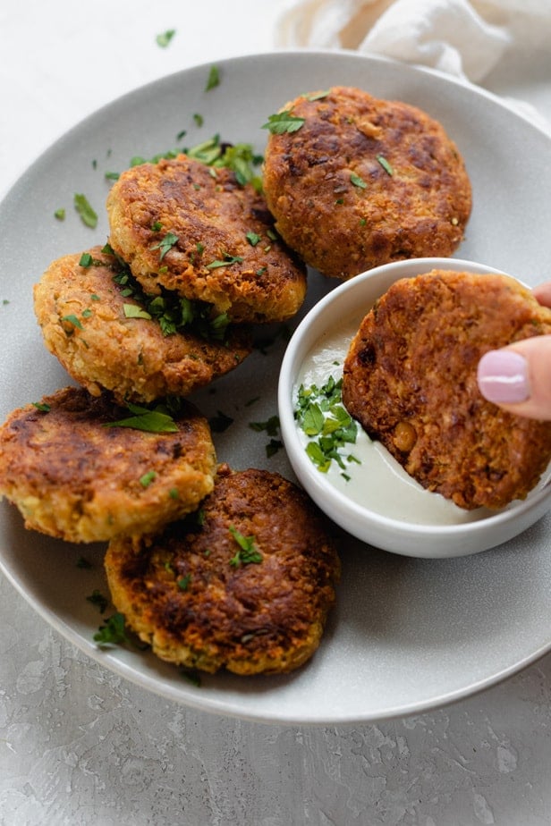 A chickpea fritter being dipped into tahini sauce