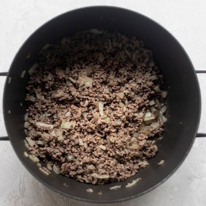 Beef and onions cooked down in a pot.