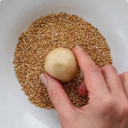 Placing cookie dough ball into the tahini mixture.