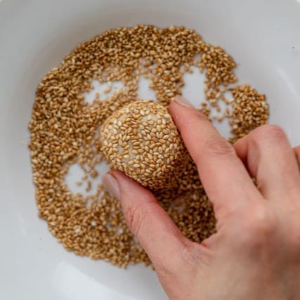 Covering the cookie dough ball with the tahini mixture.