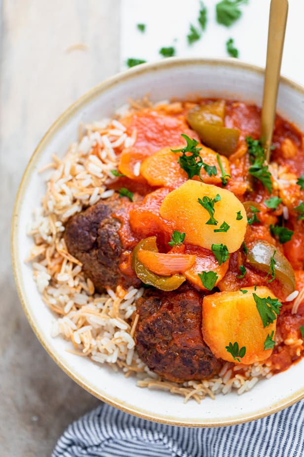 A spoon in kafta and potato stew served over rice