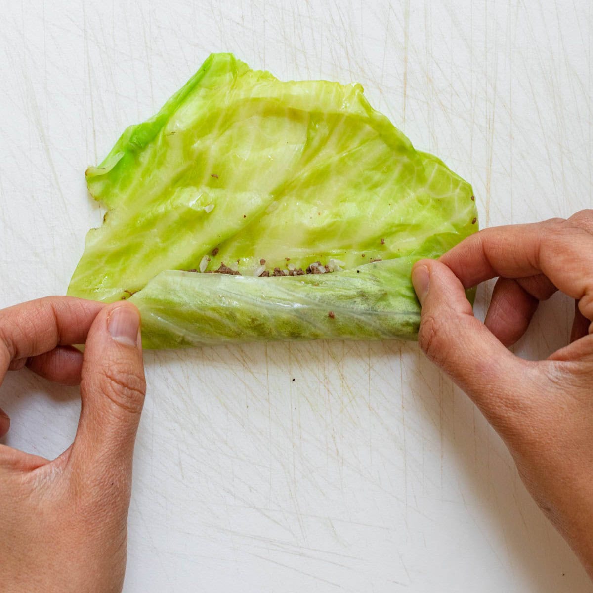 Rolling the leaf from the bottom to the top, about halfway through.