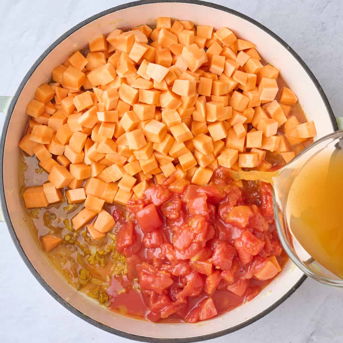 Sweet potato, tomatoes and broth being added to the pot.