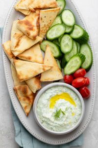 Tzatziki sauce recipe on a platter with pita and vegetables