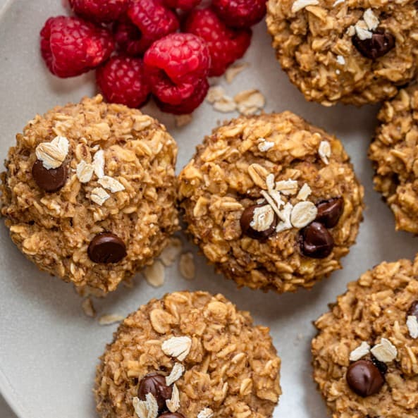 Banana oatmeal cups on a dish with raspberries.