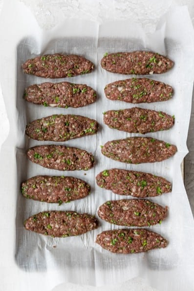 Shaped beef kafta on a baking sheet before baking.